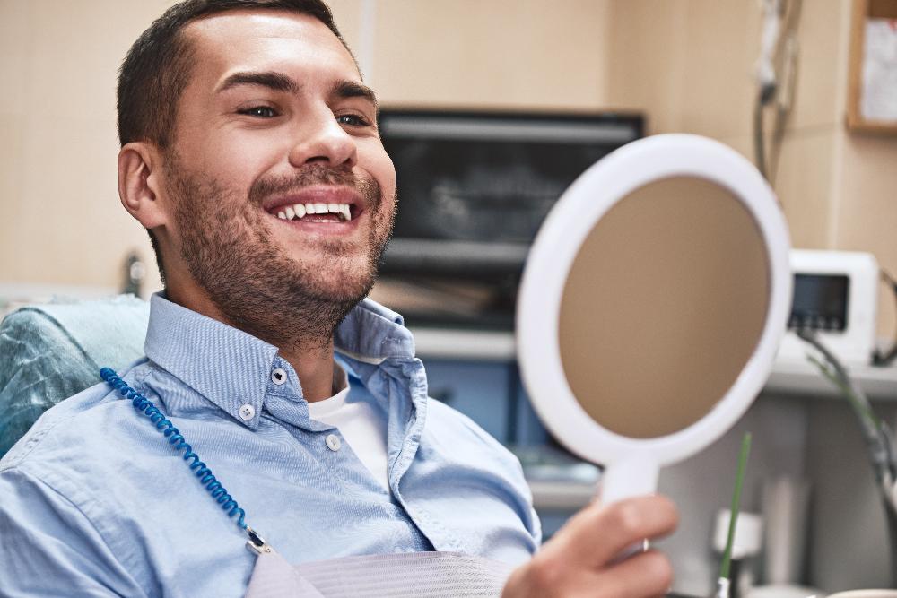 man with mirror in exam chair | dentist in bloomington in