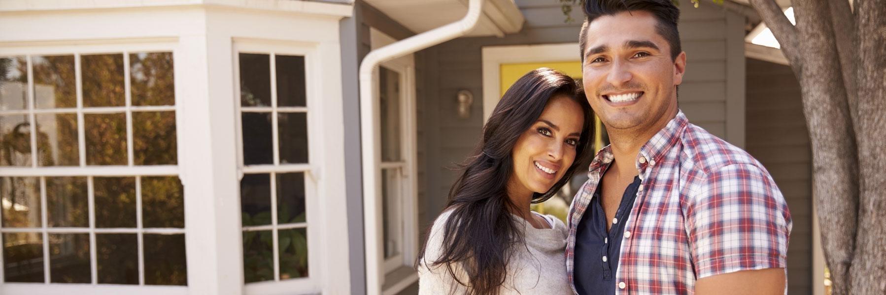 young couple smiling outside a house l dentist office bloomington in