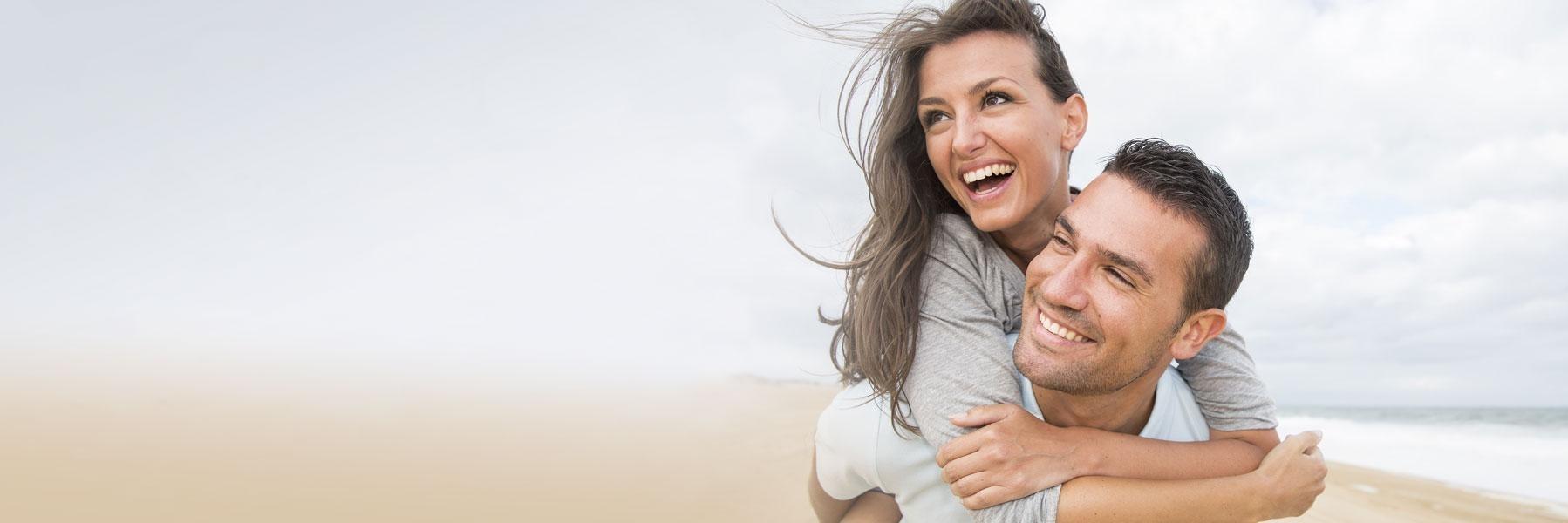 young couple hugging on beach l invisalign bloomington in