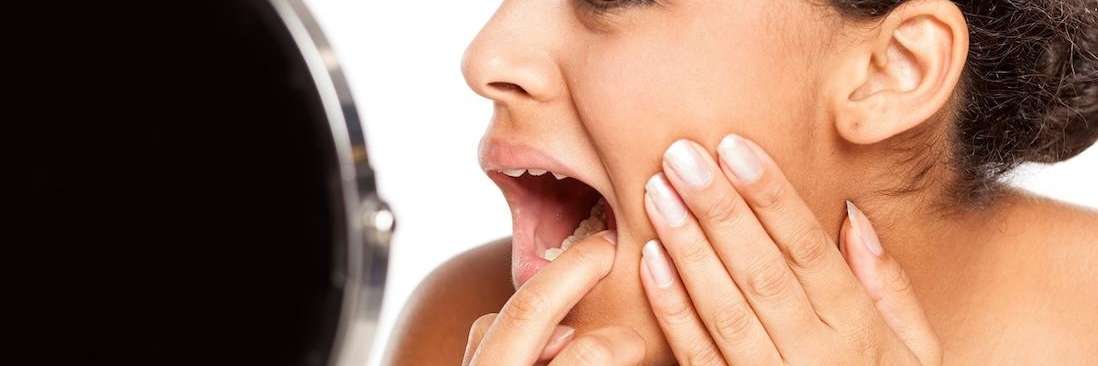 woman looking at inside mouth | dental cleanings bloomington in