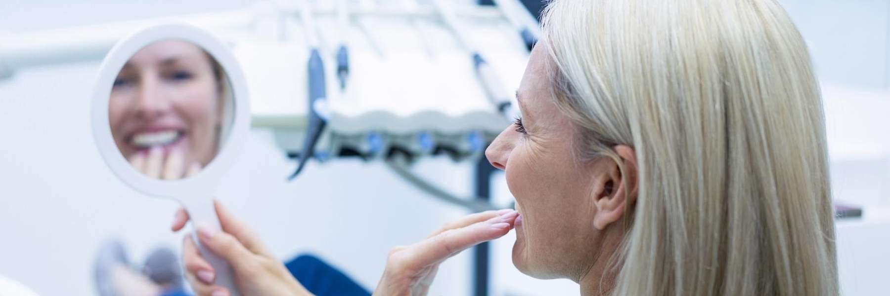 woman smiling in mirror | dentist bloomington in