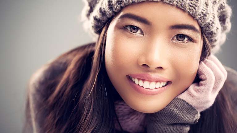 woman in snow hat smiling | dental implants bloomington in