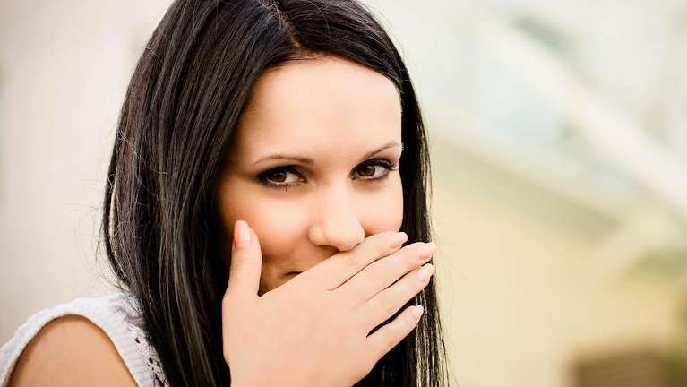 woman holding hand over mouth | dentist bloomington in