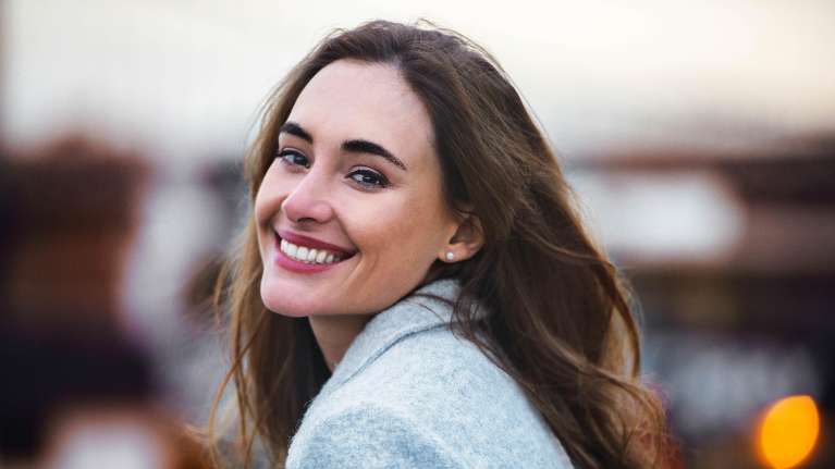 woman with brown hair smiling | dental crowns bloomington in