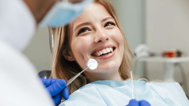 woman sitting in dentist exam chair | dentist bloomington indiana