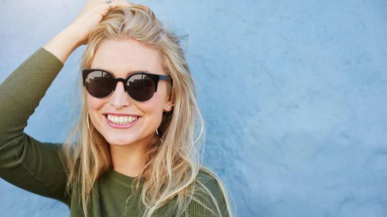 woman in black glasses smiling | cosmetic dentist bloomington in