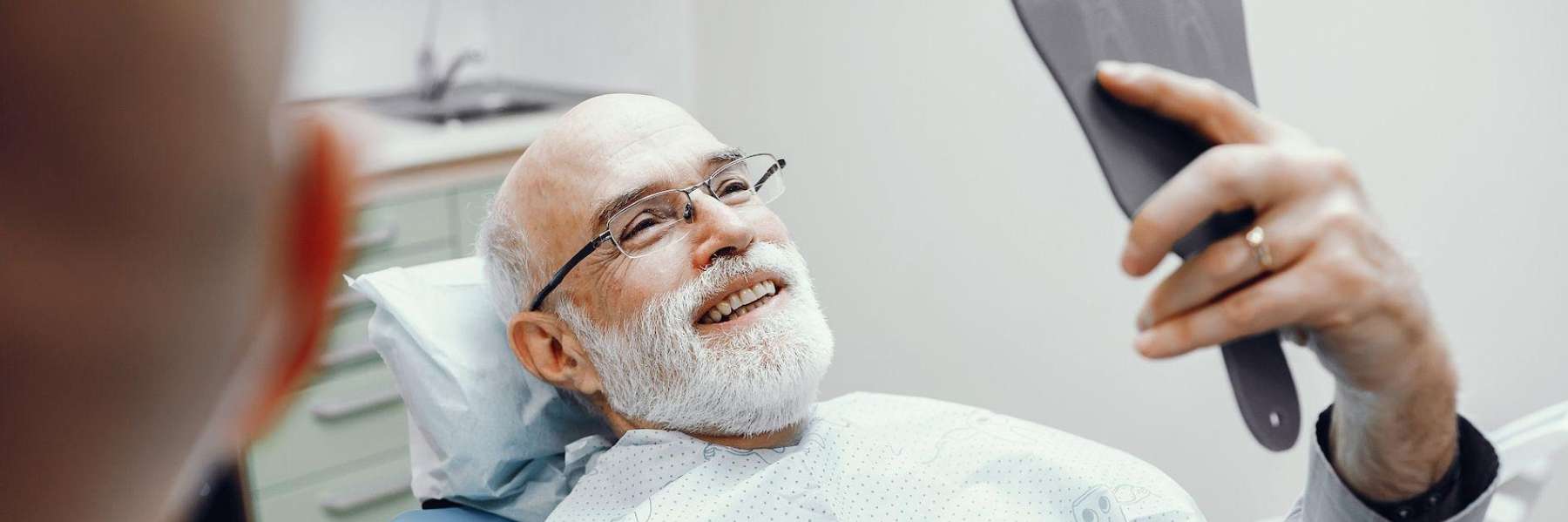 A man smiling in the mirror after his porcelain veneers procedure.