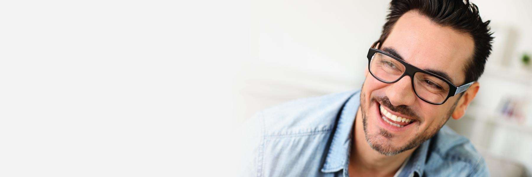 man with black glasses. smiling | dental crowns before and after