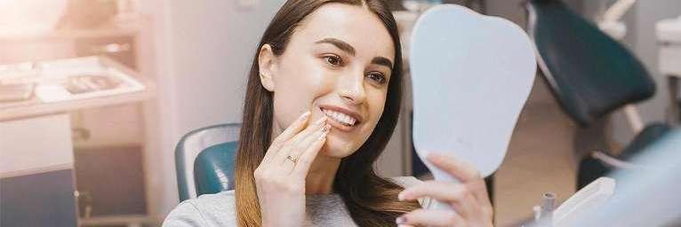 woman sitting in dental exam chair | dental implants bloomington in