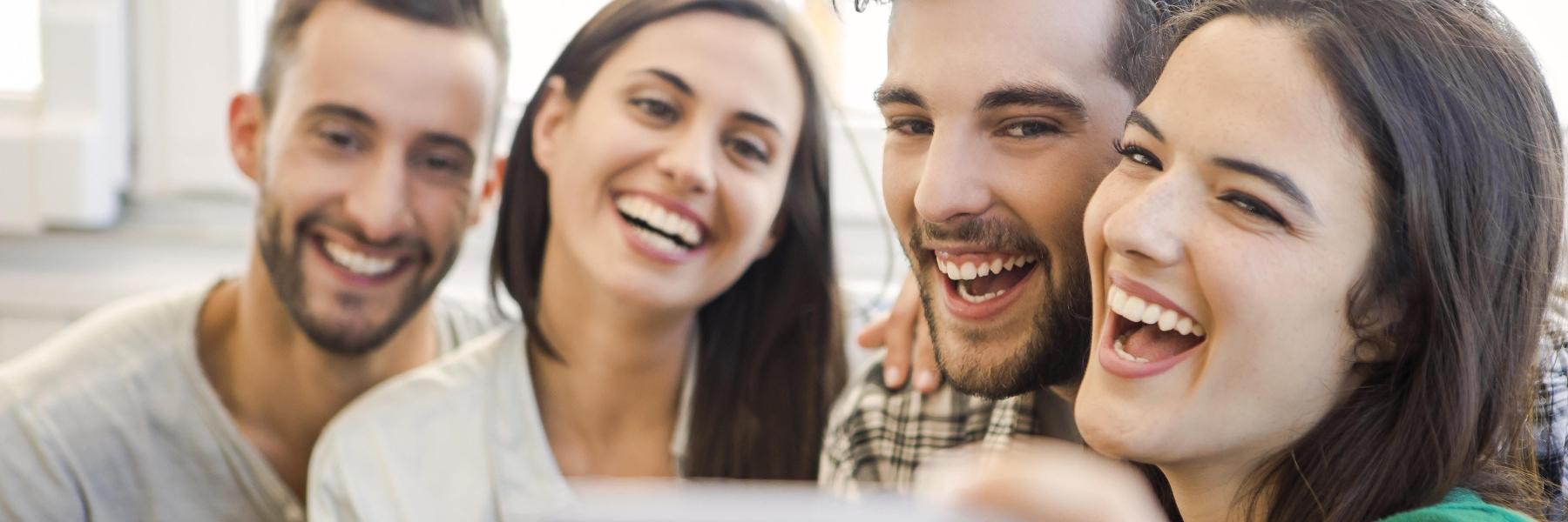 group of four adults smiling l dentists near me