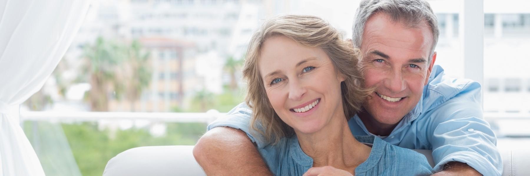 older couple sitting & hugging l dental crowns bloomington in