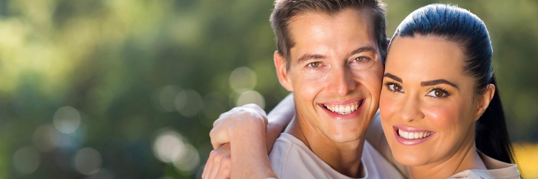 young couple smiling & hugging outside l dental cleanings bloomington in