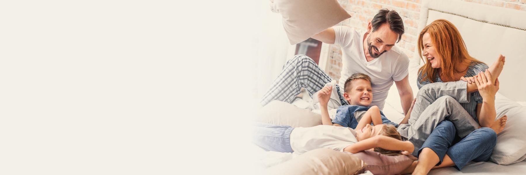 family of three playing on bed l dentist in bloomington in