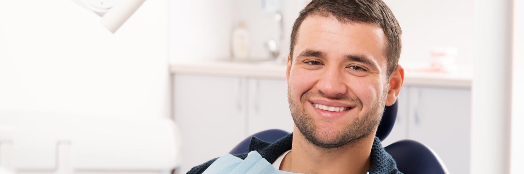 man smiling in dental exam chair l dentists in bloomington in